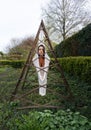 sexy woman in white transparent cotton stocking dress as a modern living sculpture outdoors in triangular rusted iron frame, Royalty Free Stock Photo