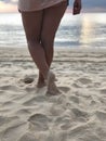 Sexy women`s tanned legs in the white fine sand of the unique Karon beach of Phuket on the background of the sea and the Golden Royalty Free Stock Photo