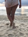 Sexy women`s tanned legs in the white fine sand of the unique Karon beach of Phuket on the background of the sea and the Golden Royalty Free Stock Photo