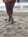 Sexy women`s tanned legs in the white fine sand of the unique Karon beach of Phuket on the background of the sea and the Golden Royalty Free Stock Photo