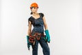 workwoman in overalls and safety helmet with tool belt holding electric drill, on white background Royalty Free Stock Photo