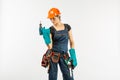 workwoman in overalls and safety helmet with tool belt holding electric drill, on white background Royalty Free Stock Photo