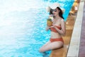 Sexy young asian woman in swimsuits in summer. beautiful woman in orange bikini with hat sitting in swimming pool with tropical Royalty Free Stock Photo
