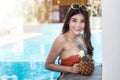 Sexy young asian woman in swimsuits in summer. beautiful woman in orange bikini with hat and tropical drink in swimming pool Royalty Free Stock Photo