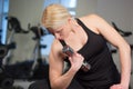 young athletics girl doing dumbbells press exercises. Fitness muscled woman in black sport clothing workout on bench in gym