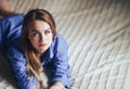 Sexy young beautiful woman with blue big eyes lond hair lying on bed at home in blue shirt Royalty Free Stock Photo