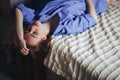 Sexy young beautiful woman with blue big eyes lond hair lying on bed at home in blue shirt Royalty Free Stock Photo