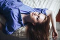 Sexy young beautiful woman with blue big eyes lond hair lying on bed at home in blue shirt Royalty Free Stock Photo