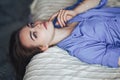 Sexy young beautiful woman with blue big eyes lond hair lying on bed at home in blue shirt Royalty Free Stock Photo