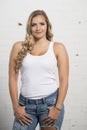 Sexy young blonde woman poses in white tank top and ripped jeans