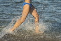 A young brunette woman or girl wearing a bikini running through the surf on a deserted tropical beach with a blue sky. Young Royalty Free Stock Photo