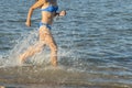 A sexy young brunette woman or girl wearing a bikini running through the surf on a deserted tropical beach with a blue sky. Young Royalty Free Stock Photo