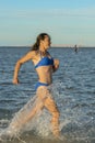 A sexy young brunette woman or girl wearing a bikini running through the surf on a deserted tropical beach with a blue sky. Young Royalty Free Stock Photo