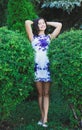 young girl between two large bushes in a short dress