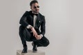 Sexy young groom in elegant tuxedo with glasses looking away and crouching