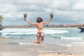 young lady in bikini jumping on the beach with fresh raw healthy pineapple fruit. Happy vacation concept. Bali.