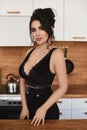 Sexy young Latino woman with big breasts in a black sexy outfit looking in camera and posing in the kitchen. Busty model Royalty Free Stock Photo