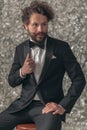 Sexy young man in elegant tuxedo looking to side and fixing jacket Royalty Free Stock Photo