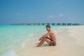 Sexy young man model sitting at the beach at the tropical island luxury resort Royalty Free Stock Photo