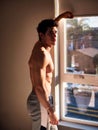 Sexy young man standing shirtless by curtains Royalty Free Stock Photo