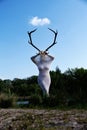 sexy young woman in a big transparent stocking dress with voluptuous curves holding a deer skull with deer antlers in front Royalty Free Stock Photo