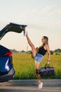 Sportive girl close car trunk with leg