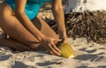 Sexy young woman sitting and holding a coconut with both hands on the golden sand of a caribbean sea beach in the mayan riviera. Royalty Free Stock Photo