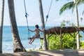 young woman sitting on the swing on the tropical beach, paradise island Bali, Indonesia. Sunny day, happy vacation Royalty Free Stock Photo