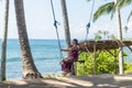 young woman sitting on the swing on the tropical beach, paradise island Bali, Indonesia. Sunny day, happy vacation Royalty Free Stock Photo