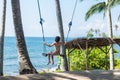 young woman sitting on the swing on the tropical beach, paradise island Bali, Indonesia. Sunny day, happy vacation Royalty Free Stock Photo