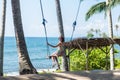 young woman sitting on the swing on the tropical beach, paradise island Bali, Indonesia. Sunny day, happy vacation Royalty Free Stock Photo