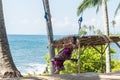 young woman sitting on the swing on the tropical beach, paradise island Bali, Indonesia. Sunny day, happy vacation Royalty Free Stock Photo