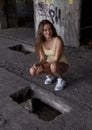 young woman in swimsuit is squatting next to the hole in the floor in abandoned building