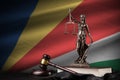 Seychelles flag with statue of lady justice, constitution and judge hammer on black drapery. Concept of judgement and guilt