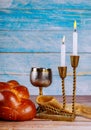 Shabbat eve table candles and cup of wine with covered challah bread