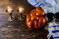 Shabbat eve table candles and cup of wine with covered challah bread