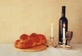 Shabbat image. challah bread, shabbat wine and candelas on wooden table. vintage filtered image