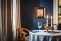 Shabbos table setting, thick closed Leather book on shabbos table with white tableloth, 2 silver candlestick in dark navy room,