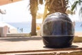Shabby black motorcycle helmet rider in scratches on the background of the red sea and palm trees under the sun for place text Royalty Free Stock Photo