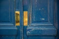 Shabby blue painted wooden door panels closeup. Shiny gold colored metal plates on rough aged wood surface of doorway. Royalty Free Stock Photo