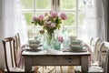 a shabby chic dining table with place settings and a vase of fresh flowers