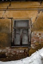 Shabby grungy cracked wall, broken windows, abandoned house, winter, poverty concept