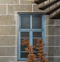 Shabby light blue wooden glass window on bricks textured wall and trees with orange leaves in front window Royalty Free Stock Photo