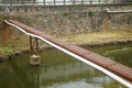 A shabby long steel pipe bridge over the river