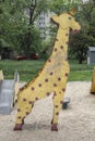 Shabby old metal giraffe sculpture on an old Soviet playground, against the backdrop of typical apartment buildings.