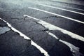 Shabby white paint on black cracked road surface texture. Old cracked traffic asphalt road background..