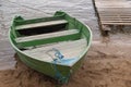 Shabby wooden boat painted green with two benches for rowing moored by rope at small board pier on shore of a bay of lake Royalty Free Stock Photo