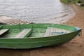 Shabby wooden boat painted green with two benches for rowing moored by rope at small board pier on shore of a bay of lake Royalty Free Stock Photo