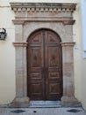 Shabby wooden door in medieval sentury style of a white old house on the street of a old greec town.