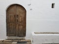 Shabby wooden door of a white old house on the street of a old greec town. Royalty Free Stock Photo